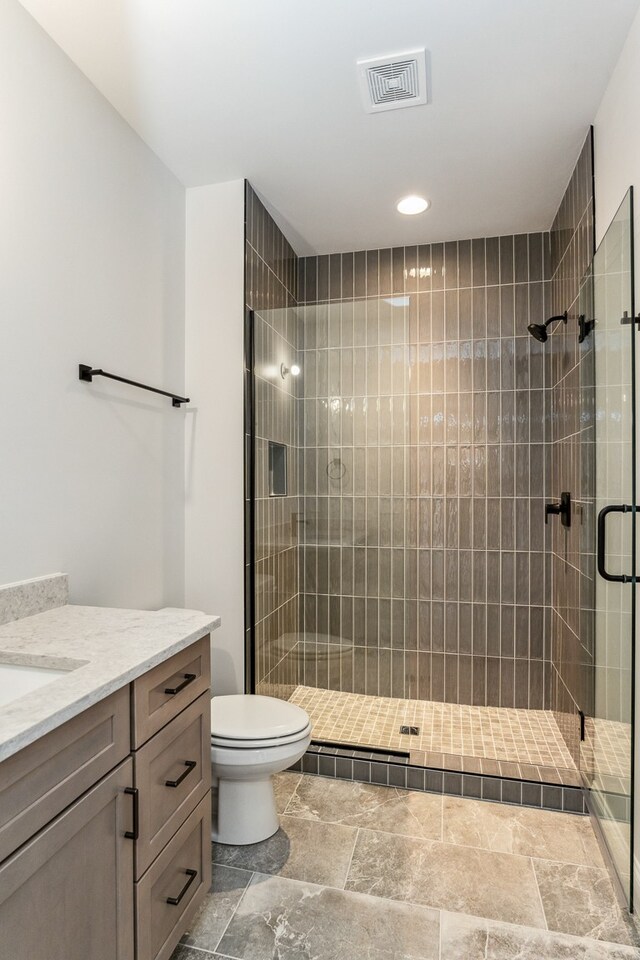 bathroom with toilet, a shower with door, and vanity