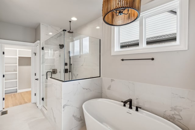 bathroom featuring a wealth of natural light and shower with separate bathtub