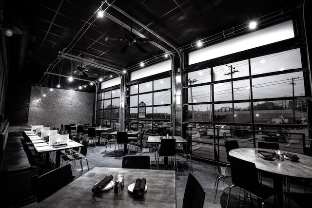 dining space featuring a towering ceiling, concrete floors, ceiling fan, and floor to ceiling windows