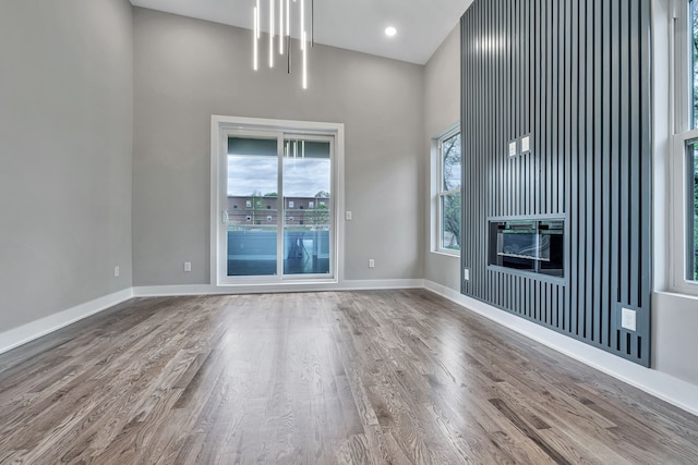 unfurnished living room with a wealth of natural light, hardwood / wood-style floors, and a towering ceiling