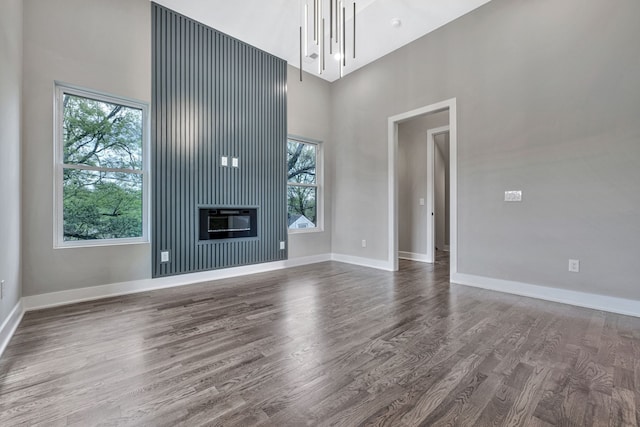 unfurnished living room with a high ceiling, a fireplace, and wood-type flooring