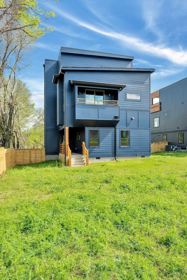 back of house with a lawn and a balcony