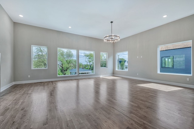 unfurnished living room featuring a notable chandelier, a healthy amount of sunlight, and hardwood / wood-style flooring