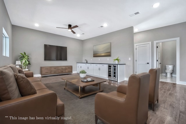 living room featuring sink, ceiling fan, dark hardwood / wood-style floors, and beverage cooler