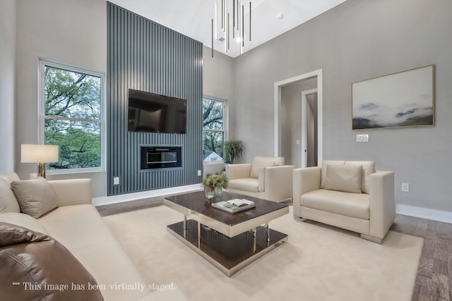 living room with a high ceiling, hardwood / wood-style flooring, and a healthy amount of sunlight