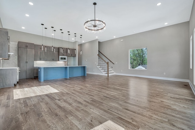 kitchen with light hardwood / wood-style flooring, decorative backsplash, decorative light fixtures, and stainless steel microwave