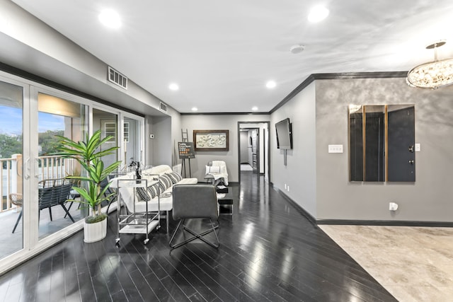 living room featuring dark hardwood / wood-style flooring, crown molding, and a notable chandelier