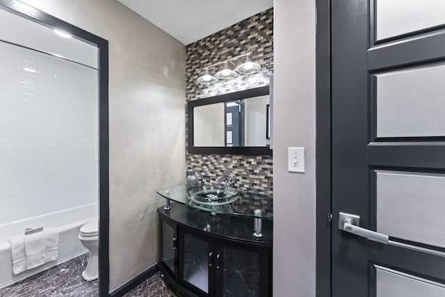 bathroom with vanity, backsplash, toilet, and a bathing tub