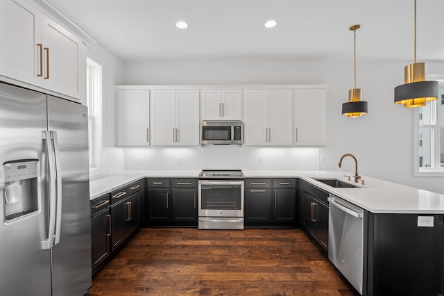 kitchen featuring dark hardwood / wood-style floors, hanging light fixtures, kitchen peninsula, white cabinetry, and appliances with stainless steel finishes