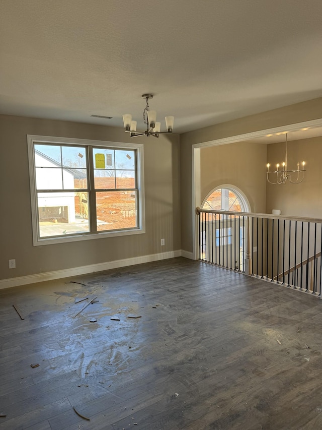 spare room with dark hardwood / wood-style flooring and a chandelier