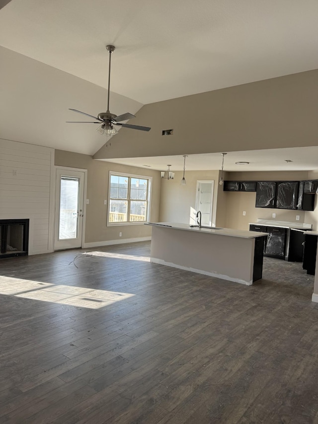 unfurnished living room featuring ceiling fan, vaulted ceiling, dark wood-type flooring, and sink