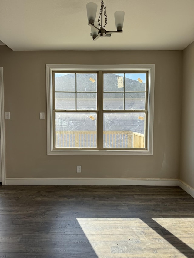 empty room featuring dark hardwood / wood-style flooring and an inviting chandelier