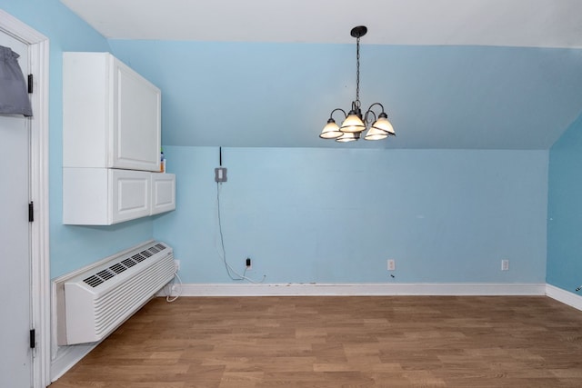 interior space featuring hardwood / wood-style flooring, a wall mounted AC, and an inviting chandelier