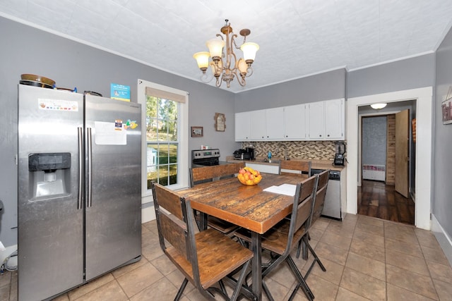 kitchen featuring hanging light fixtures, stainless steel appliances, crown molding, white cabinets, and tasteful backsplash