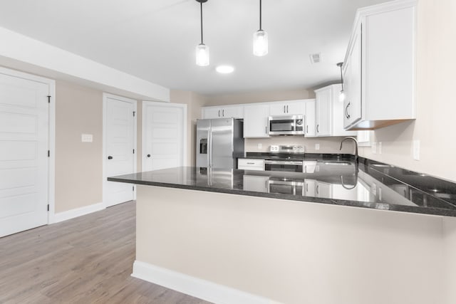 kitchen with dark stone countertops, stainless steel appliances, a peninsula, and a sink