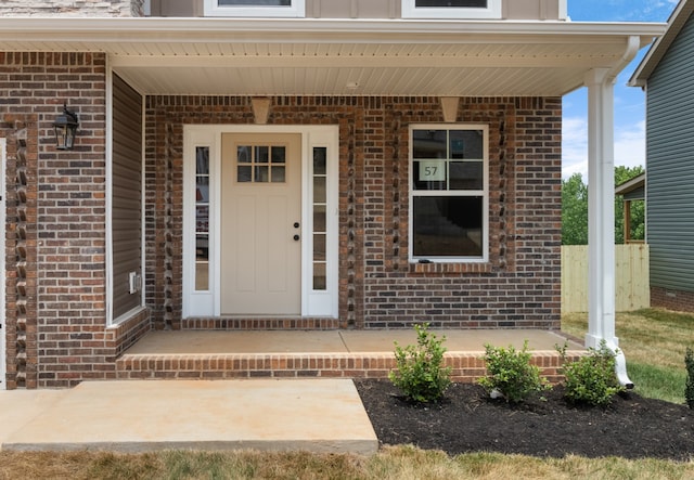 doorway to property featuring covered porch and brick siding