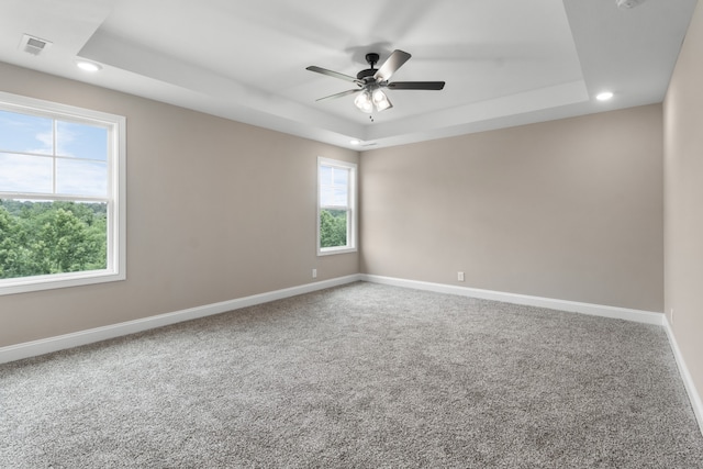 carpeted empty room with a raised ceiling and ceiling fan