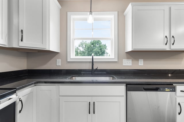 kitchen with pendant lighting, sink, white cabinetry, stainless steel dishwasher, and dark stone counters