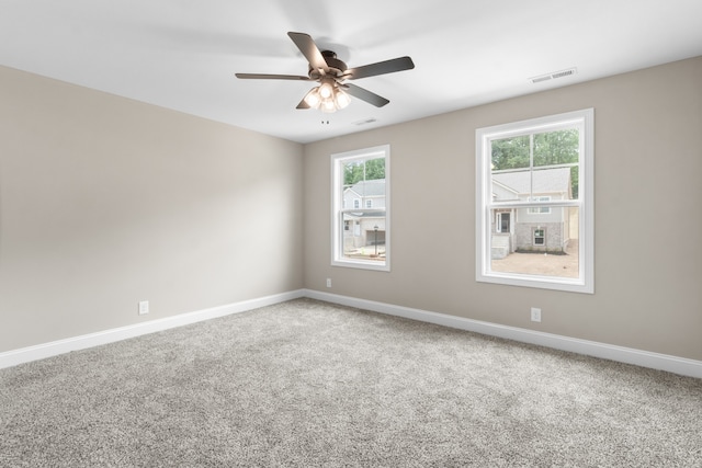 spare room with carpet flooring, visible vents, and baseboards