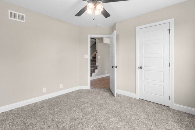 unfurnished bedroom featuring a ceiling fan, visible vents, light carpet, and baseboards