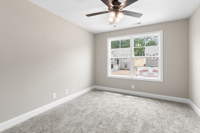 carpeted empty room featuring a ceiling fan, visible vents, and baseboards