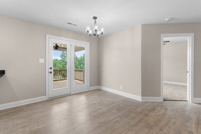 unfurnished room with an inviting chandelier and light hardwood / wood-style flooring