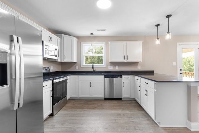 kitchen with a peninsula, a sink, visible vents, appliances with stainless steel finishes, and dark countertops