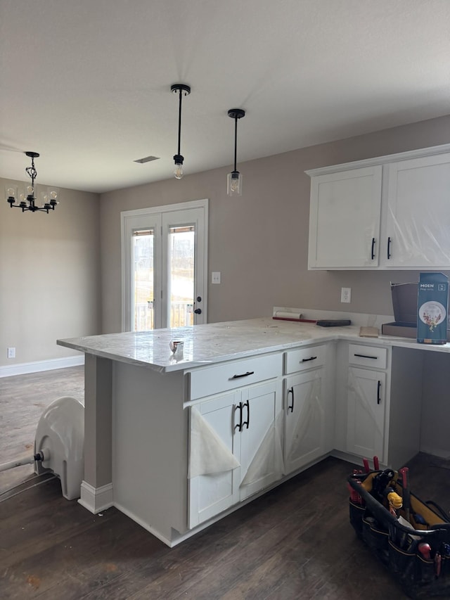 kitchen featuring a peninsula, dark wood-type flooring, decorative light fixtures, and white cabinets