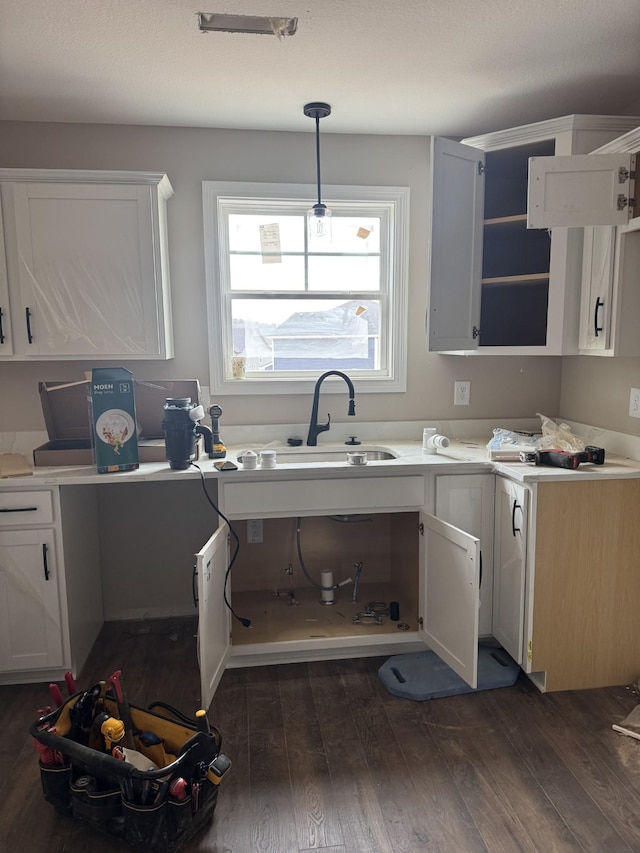 kitchen with open shelves, dark wood-style flooring, a sink, and white cabinetry