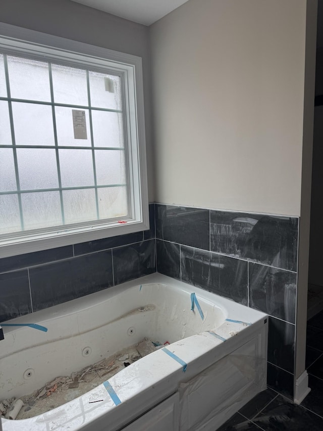 bathroom featuring a wealth of natural light and a jetted tub