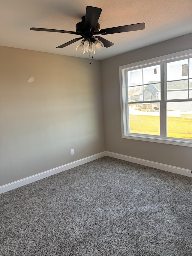 empty room with carpet floors, a ceiling fan, and baseboards