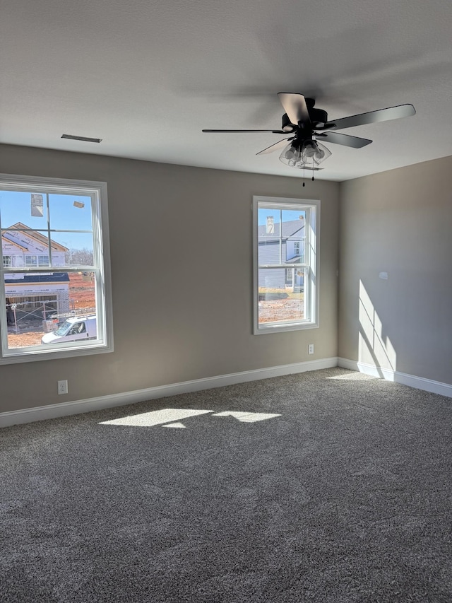 empty room featuring a ceiling fan, carpet, visible vents, and baseboards