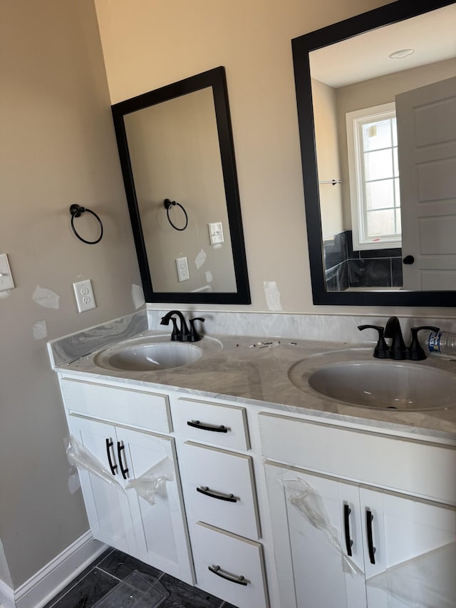 bathroom featuring double vanity, a sink, and baseboards