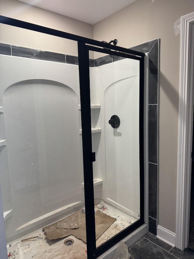 bathroom featuring marble finish floor and a shower stall