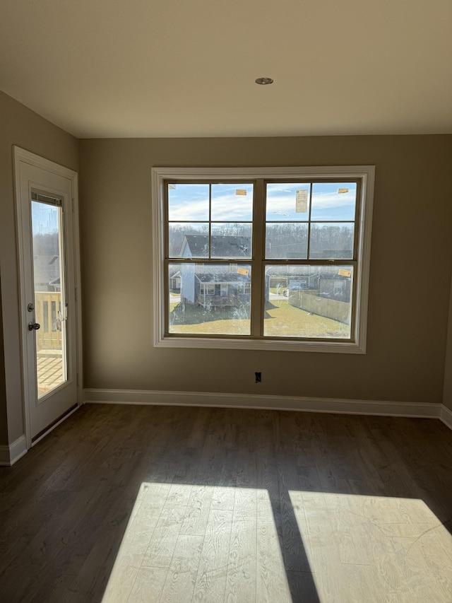 unfurnished room featuring dark wood-type flooring and plenty of natural light