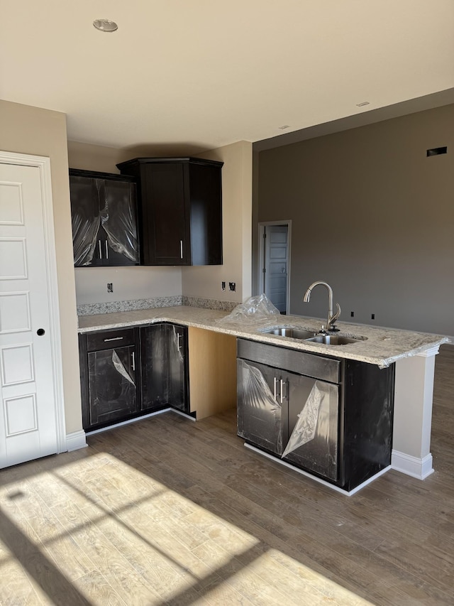 kitchen featuring hardwood / wood-style flooring, light stone countertops, sink, and kitchen peninsula