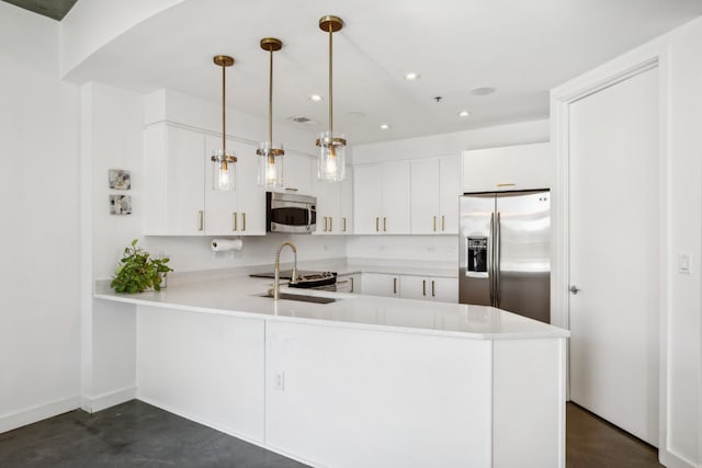 kitchen featuring appliances with stainless steel finishes, kitchen peninsula, white cabinets, and pendant lighting