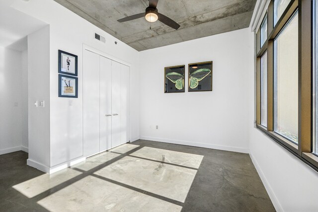 unfurnished bedroom with a closet, concrete floors, and ceiling fan