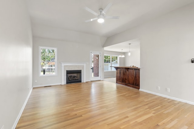 unfurnished living room with ceiling fan with notable chandelier and light hardwood / wood-style flooring