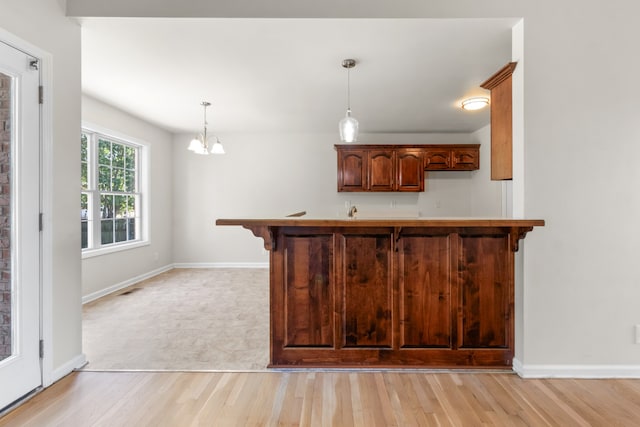 kitchen with a kitchen bar, light hardwood / wood-style flooring, hanging light fixtures, and a chandelier