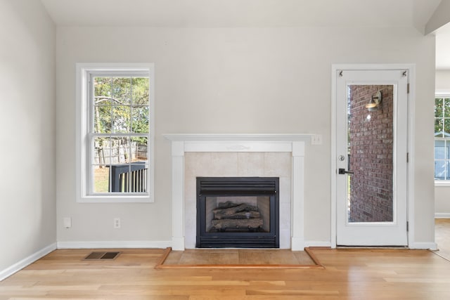 unfurnished living room featuring light wood-type flooring and a tiled fireplace