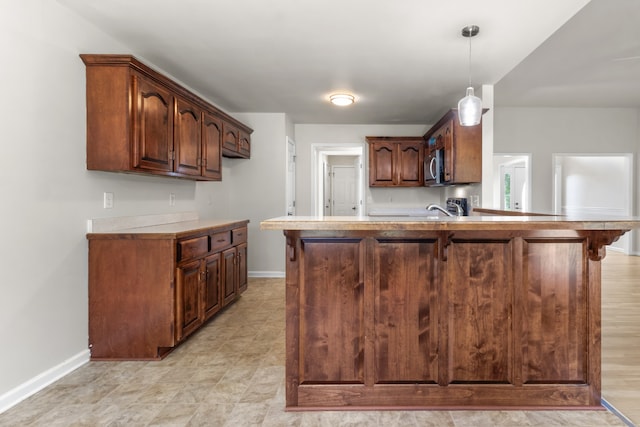 kitchen featuring dark brown cabinets, kitchen peninsula, sink, and decorative light fixtures