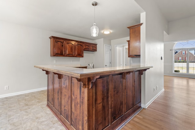 kitchen featuring kitchen peninsula, a kitchen bar, and light hardwood / wood-style floors