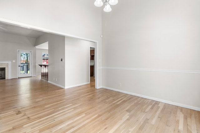 unfurnished living room featuring a fireplace, light hardwood / wood-style floors, and a chandelier