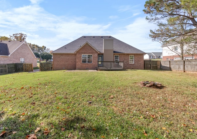 rear view of house with a yard and a wooden deck