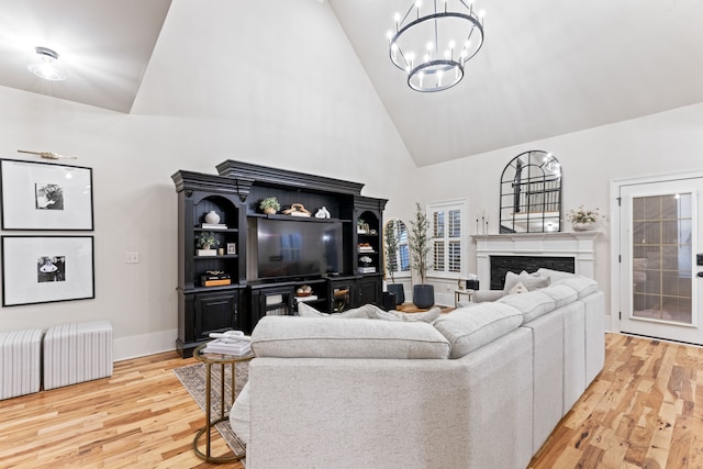 living room with an inviting chandelier, high vaulted ceiling, and light wood-type flooring