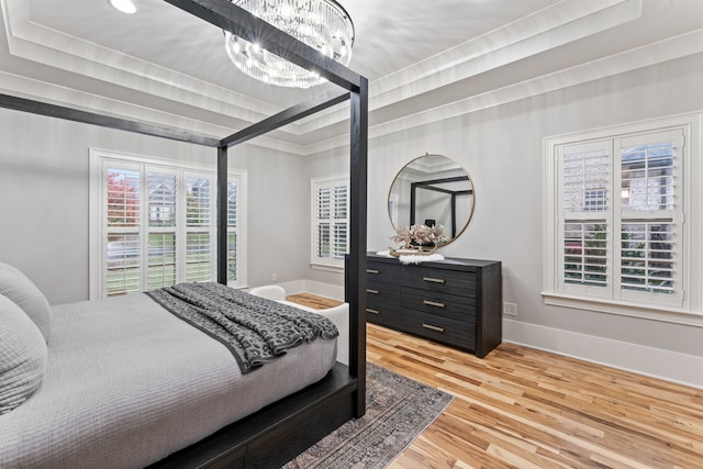 bedroom featuring a chandelier, hardwood / wood-style flooring, and a tray ceiling