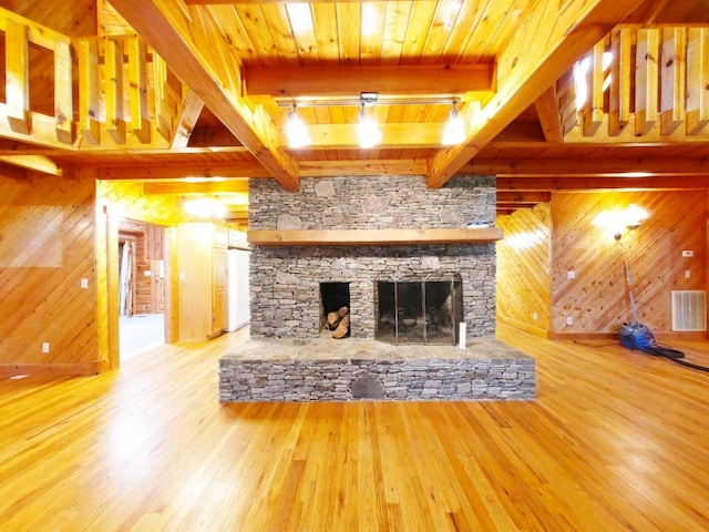 unfurnished living room with beam ceiling, wooden walls, and wood-type flooring