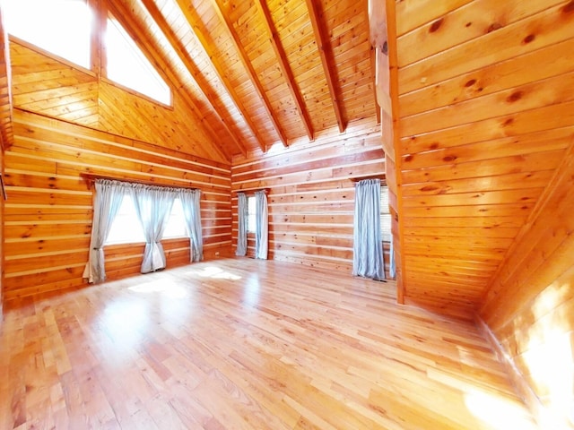 unfurnished living room with wood walls, wood ceiling, light hardwood / wood-style floors, beamed ceiling, and high vaulted ceiling