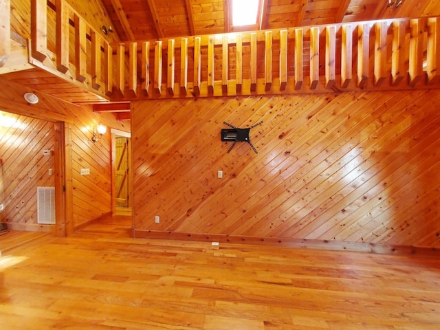 interior space featuring wood walls, beam ceiling, wooden ceiling, and hardwood / wood-style floors